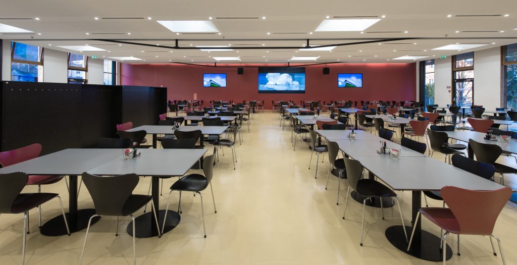Kantine als Veranstaltungsraum mit großen Screens, Mikrofonen und Beschallung